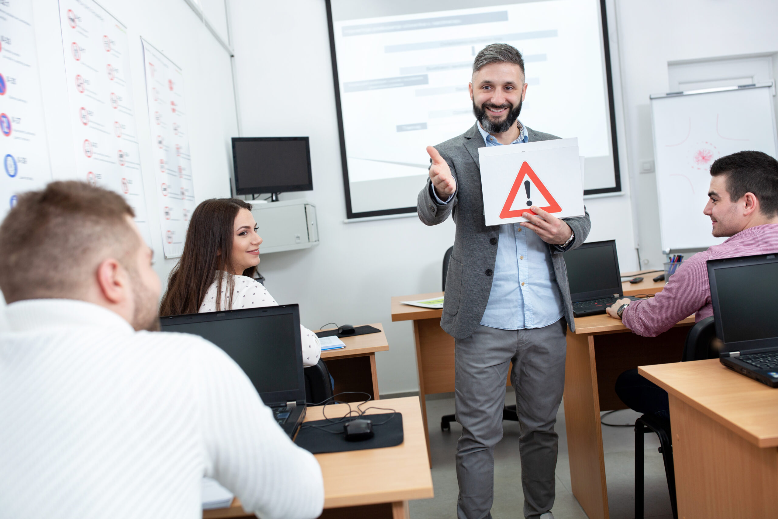Driving instructor asking students about the traffic sign he is holding in the classroom